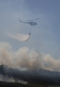 The chopper drops a load of water directly upslope from firefighters.