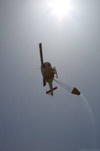 The fire helicopter passes directly overhead after releasing a load.